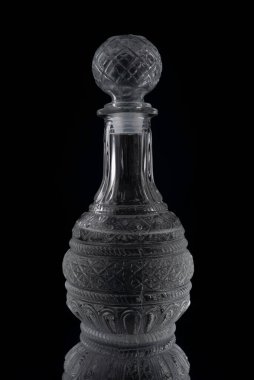 Sürahide votka ve masada yansıması olan bir bardak. Siyah bir arkaplanda.