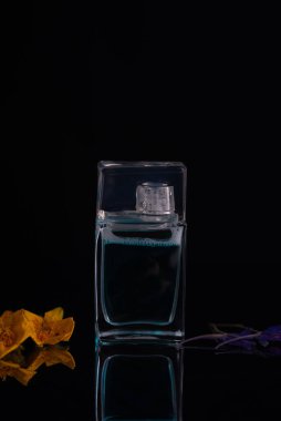 Siyah arka planda bir parfüm şişesi bahar çiçeği aroması.