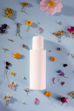Beyaz plastik kozmetik ürün kremi mavi çiçekli arka plan kozmetik kompozisyon üst görünüm, düz yatıyordu.
