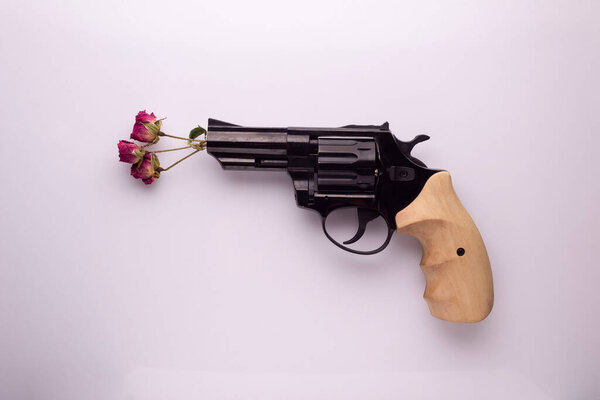 Pink hipster handgun on blue pastel background with flowers. Piece flat lay concept.