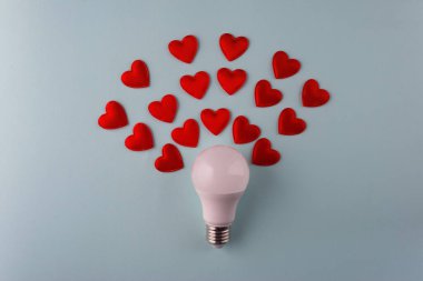 Ampulün etrafındaki kalplerden gelen hafif aşk kavramı mavi arkaplan minimalizmi.