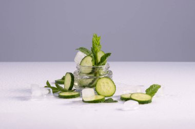 Beyaz arka planda cam bir kapta bulunan doğal aloe, salatalık ve buz özlerine dayanan nemlendirici kozmetikler..