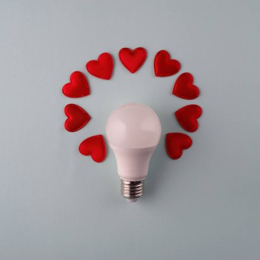 Ampulün etrafındaki kalplerden gelen hafif aşk kavramı mavi arkaplan minimalizmi.
