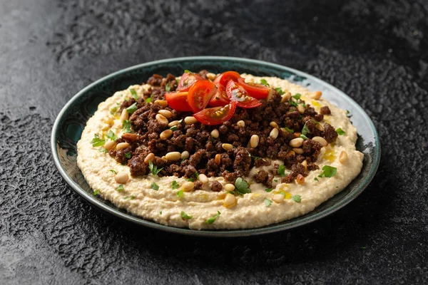 Hummus with spiced ground beef, olive oil, tomatoes and toasted pine nuts.