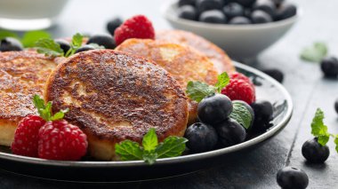 Yabanmersini, ahududu, çilek reçeli ve nane yaprağı ile servis edilen süzme peynirli krepler sağlıklı vejetaryen protein kahvaltısı..