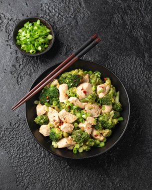 Kızarmış tavuk ve brokoliyi siyah kasede karıştır..