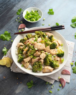 Kızarmış tavuk ve brokoli ile pilavı beyaz tabakta karıştır..