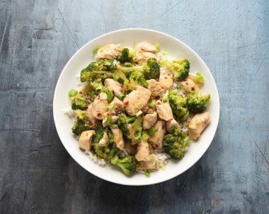 Kızarmış tavuk ve brokoli ile pilavı beyaz tabakta karıştır..