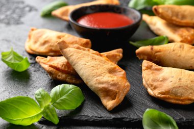 Siyah tahtada servis edilen bolonez ile taze pişmiş mini calzone..