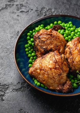 Mavi tabakta yeşil bezelyeli fırında tavuk budu..