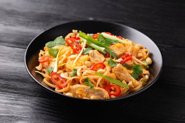 Yumurtalı Pad Thai tavuğu, fasulye filizi, fıstık ve taze soğan..