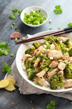 Kızarmış tavuk ve brokoli ile pilavı beyaz tabakta karıştır..