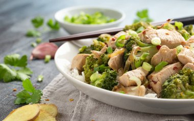 Kızarmış tavuk ve brokoli ile pilavı beyaz tabakta karıştır..