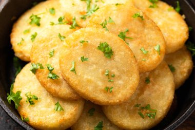 Healthy Cauliflower hash browns in cast iron frying pan on rustic wooden table.