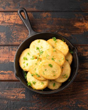 Healthy Cauliflower hash browns in cast iron frying pan on rustic wooden table.