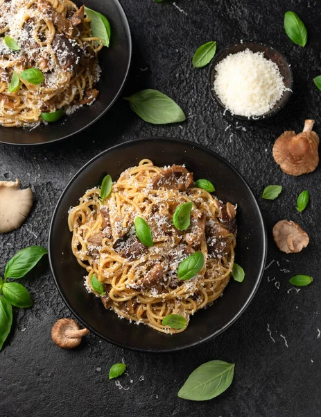 Porcini and woodland mushrooms pasta with pecorino cheese, basil in black bowl.