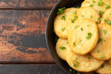 Healthy Cauliflower hash browns in cast iron frying pan on rustic wooden table.
