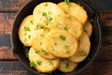 Healthy Cauliflower hash browns in cast iron frying pan on rustic wooden table.