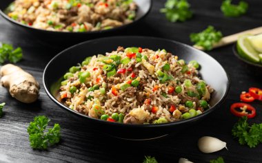 Asian Beef Fried Rice with eggs and vegetables in black bowl.