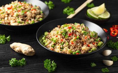 Asian Beef Fried Rice with eggs and vegetables in black bowl.