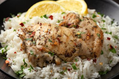 Izgara tavuk butları, siyah kasede pilav ile servis edilir..