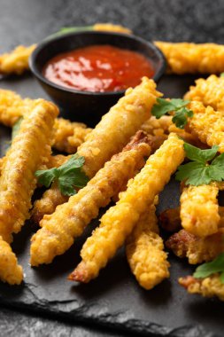Fried Vegan jackfruit and oyster prawns in crispy batter served on black slate with chili dip sauce.