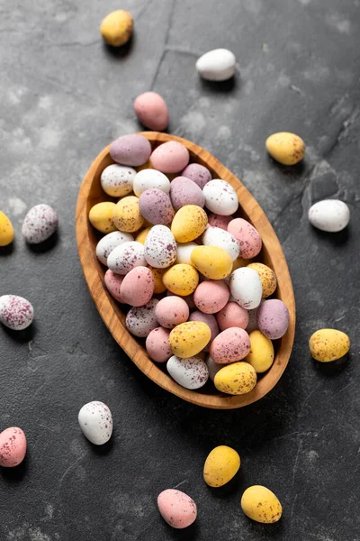 Easter mini eggs, chocolate candy in wooden bowl.