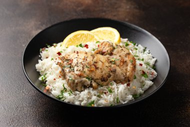 Izgara tavuk butları, siyah kasede pilav ile servis edilir..