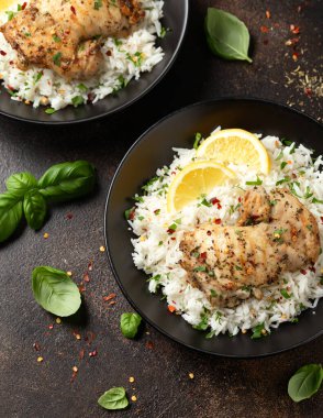 Izgara tavuk butları, siyah kasede pilav ile servis edilir..