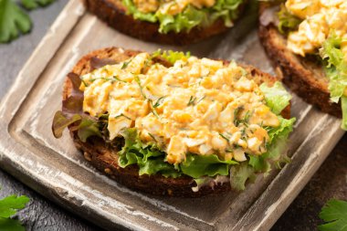 Tahtada sebzeli ve otlu yumurta salatalı sandviçler. Sağlıklı yemek.