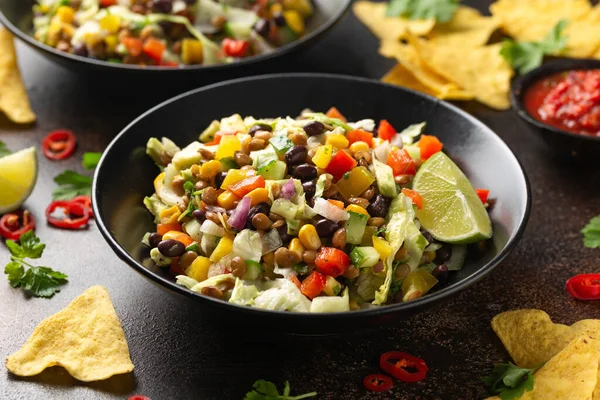 Mexican style salad of black beans, lentils, corn, tomato and lettuce with a salsa and tortilla chips.