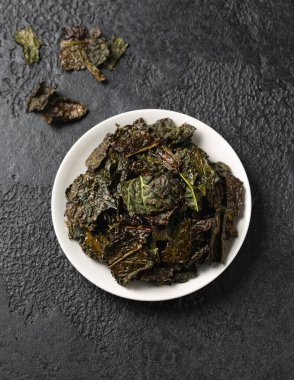 Lezzetli bir Kale cipsi, beyaz tabakta atıştırmalık. Sağlıklı sebze yemeği...