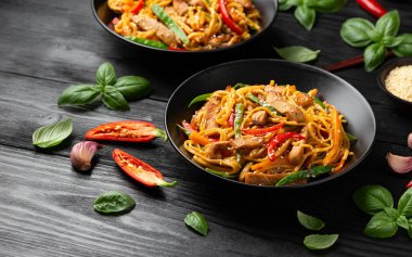 Kızartma chow mein noodle ile siyah kasede domuz eti ve sebze. Asya usulü yemek..