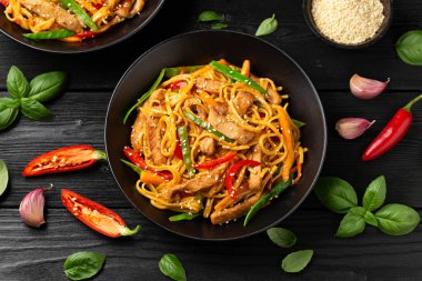 Kızartma chow mein noodle ile siyah kasede domuz eti ve sebze. Asya usulü yemek..