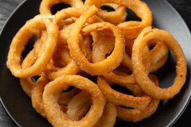 Çıtır çıtır kızarmış soğan halkaları siyah tabakta..