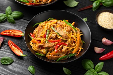 Kızartma chow mein noodle ile siyah kasede domuz eti ve sebze. Asya usulü yemek..