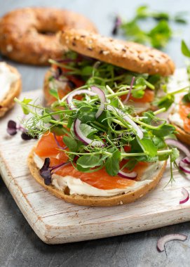 Tütsülenmiş somon ve bezelyeli yumuşak peynirli simit ve mor salata ve kırmızı soğan. Protein paketlenmiş kahvaltı konsepti.