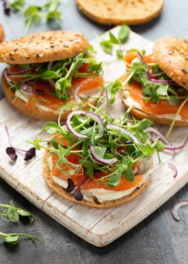 Tütsülenmiş somon ve bezelyeli yumuşak peynirli simit ve mor salata ve kırmızı soğan. Protein paketlenmiş kahvaltı konsepti.