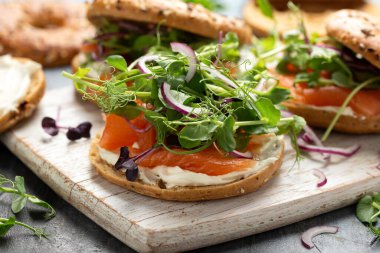 Tütsülenmiş somon ve bezelyeli yumuşak peynirli simit ve mor salata ve kırmızı soğan. Protein paketlenmiş kahvaltı konsepti.