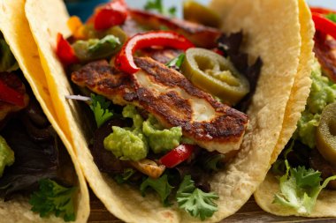 Kavrulmuş soğan ve dolmalık biber, avokado guacamole ve biber turşusu ile kızarmış halloumi fajitas..