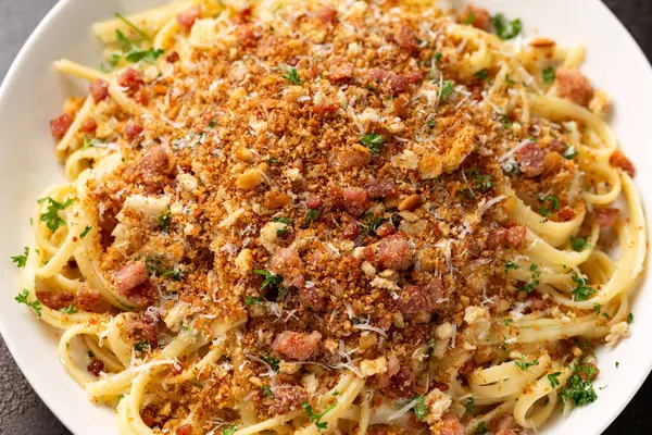 Kızarmış ekmek kırıntıları, pastırma ve parmesan peynirli spagetti.