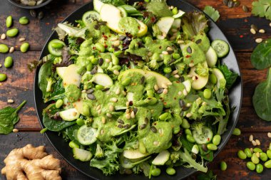 Ispanak, brokoli, elma, salatalık ve edamame fasulyeli süper yeşil salata avokado, elma sirkesi ve zeytinyağı sosu, çam fıstığı ve balkabağı çekirdeği ile servis edilir..