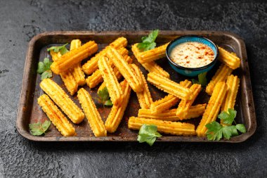 Kırmızı biber ve taze maydanozla servis edilen gevrek ve altın patatesli churros..