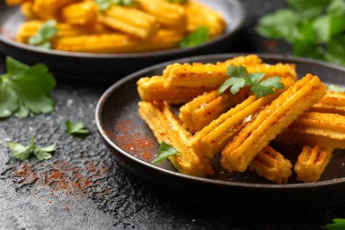 Kırmızı biber ve taze maydanozla servis edilen gevrek ve altın patatesli churros..