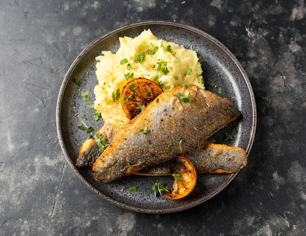 Pan fried sea bass fillets served with mashed potatoes and caramelised lemon.