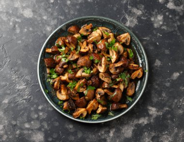 Lezzetli kızarmış mantarlar, bitkiler ve maydanozlu tabaklar.