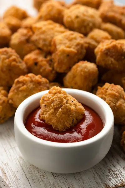 Crispy Popcorn Chicken with ketchup sauce on white wooden board.