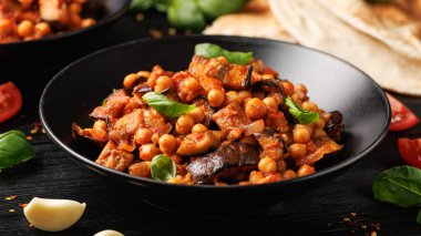 Patlıcan ve domates soslu nohut güveci, sarımsak, baharat ve pide ekmeği. Sağlıklı yemek..