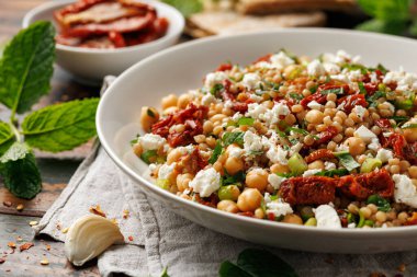 Güneşte kurutulmuş domatesli, nohut ve peynirli inci kuskus salatası. sağlıklı yiyecekler.