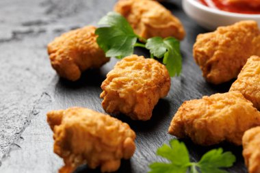 Ev yapımı kızarmış tavuk nuggetları bir taş tahtada servis edilir..